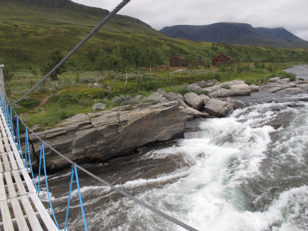 Die Brücke über den Rostaelva Fluss mit den Rostahytta im Hintergrund